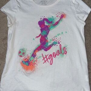 A white soccer shirt with a girl kicking a soccer ball